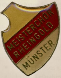 Vereinsnadel des Quartettvereins &sbquo;Rheingold&lsquo; M&uuml;nster 1919 zum Aufstieg zum Meisterchor im Jahr 1968 in den Farben Gold, Rot und Silber.