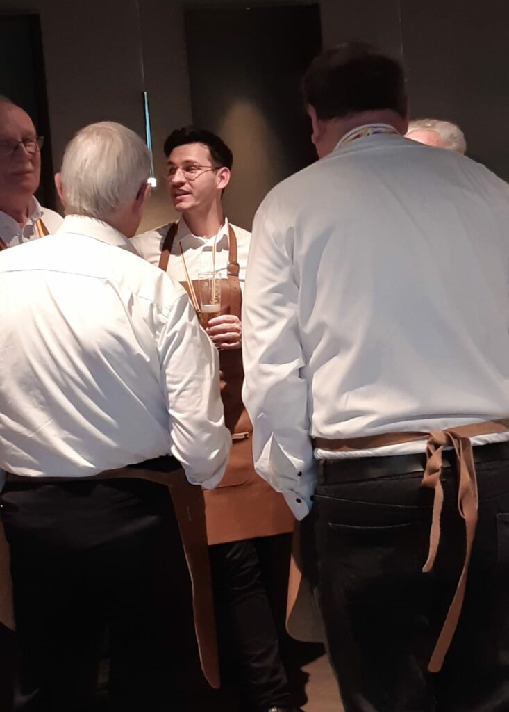 Eine Gruppe von S&auml;ngern der Fidelen Bierkutscher h&ouml;rt aufmerksam Chorleiter Simon Wiesrecker zu, der nach dem Auftritt beim SKA M&uuml;nster sein Feedback gibt.